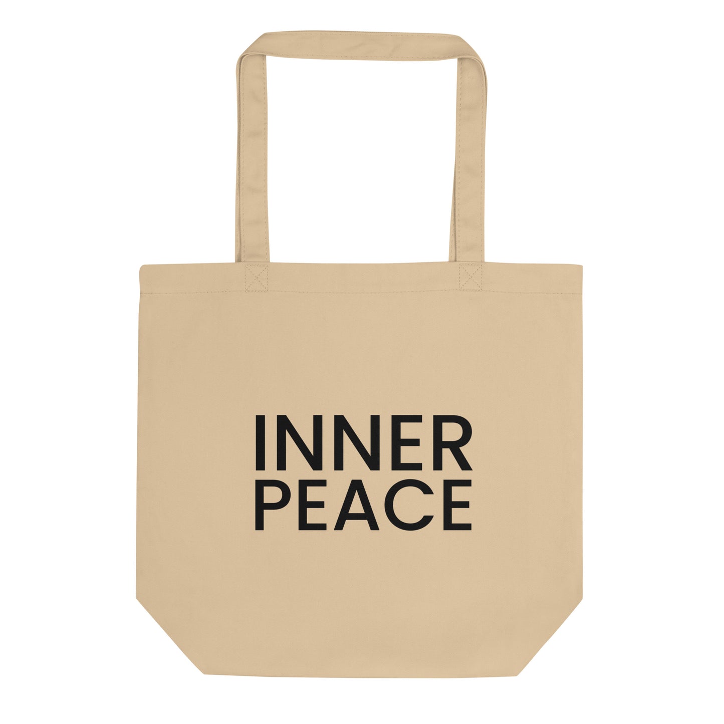 A light beige tote bag with the phrase "INNER PEACE" printed on the front in a bold, black, sans-serif font. The text is in all caps and stacked on two lines. The slogan represents a state of mental and spiritual calm, encouraging a feeling of contentment and serenity that comes from within.