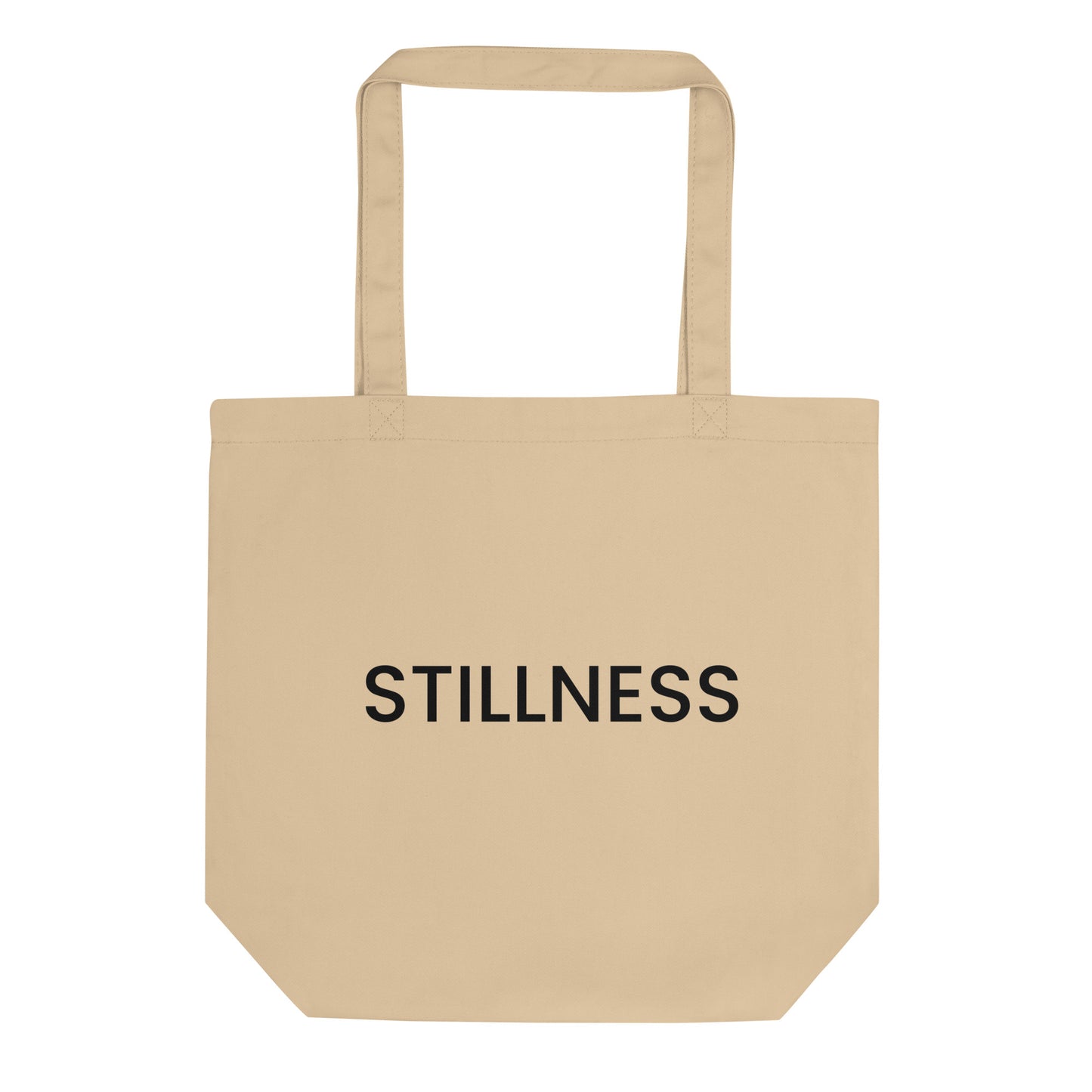 A light beige tote bag with the word "STILLNESS" printed on the front in a bold, black, sans-serif font. The text is in all caps and centered on one line. The word represents a state of calm and quiet, encouraging a practice of finding peace amid the busyness of daily life.