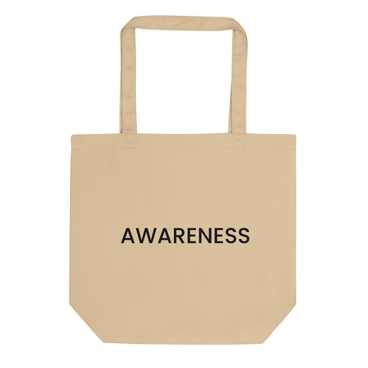 A light beige tote bag with the word "AWARENESS" printed on the front. The text is in a bold, black, sans-serif font, centered on one line, and is in all caps.