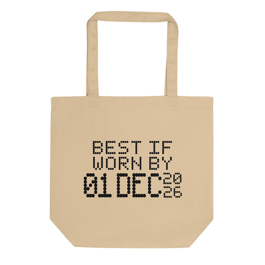 A minimalistic eco tote bag with the phrase “Best If Worn By 01 December 2026” printed in a bold, dot-matrix-style font. The design resembles an expiration date label, blending humor with clean, modern aesthetics.