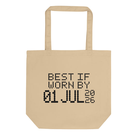 A minimalistic eco tote bag with the phrase “Best If Worn By 01 July 2026” printed in a bold, dot-matrix-style font. The design resembles an expiration date label, blending humor with clean, modern aesthetics.