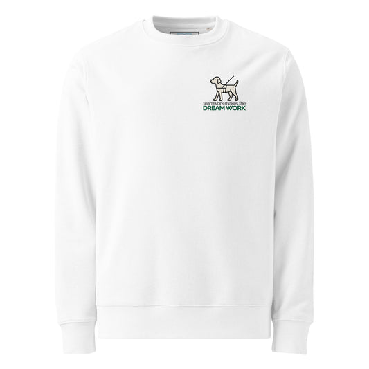 A centered illustration of a cream-colored guide dog in black harness appears above the phrase “teamwork makes the DREAM WORK.” The text uses light gray sans-serif for the top line and bold forest green for the bottom, creating a clean, balanced layout that promotes accessibility, partnership, and peace.