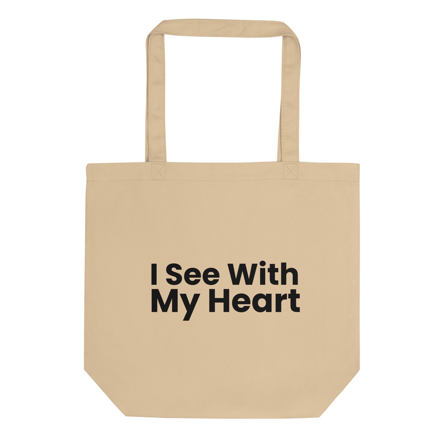 A tan-colored tote bag is displayed against a white background. The phrase "I See With My Heart" is printed in a bold, black, sans-serif font in the center of the bag. The text is stacked in three lines.