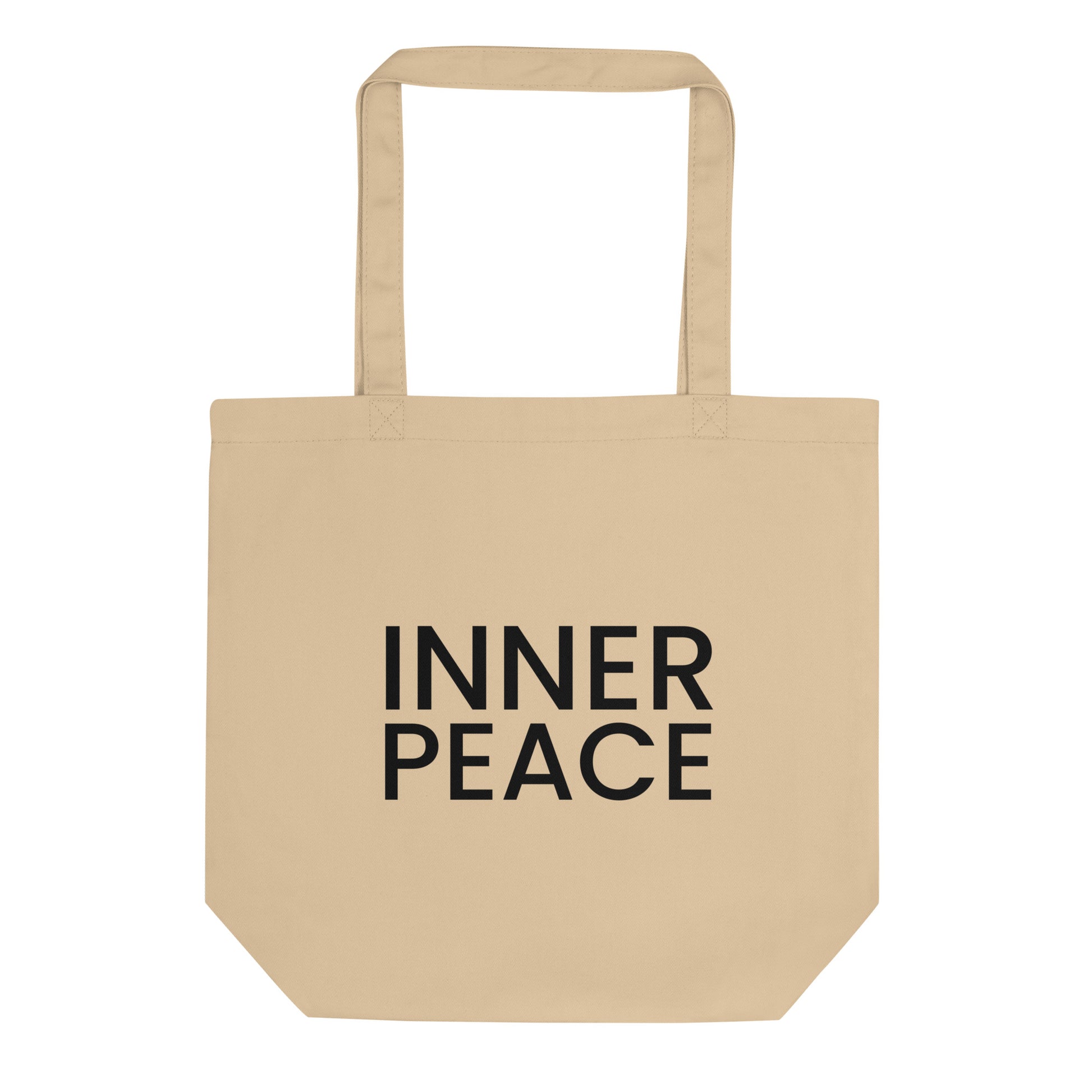 A light beige tote bag with the phrase "INNER PEACE" printed on the front in a bold, black, sans-serif font. The text is in all caps and stacked on two lines. The slogan represents a state of mental and spiritual calm, encouraging a feeling of contentment and serenity that comes from within.