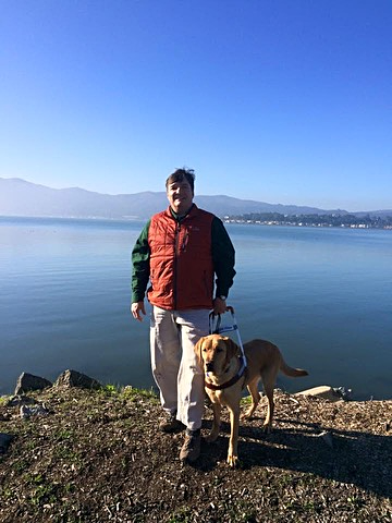This is a photo of Kevin with his guide dog Fulton with the San Francisco Bay in the background.  Forever in our hearts Fulton (June 2013-August 2025).  